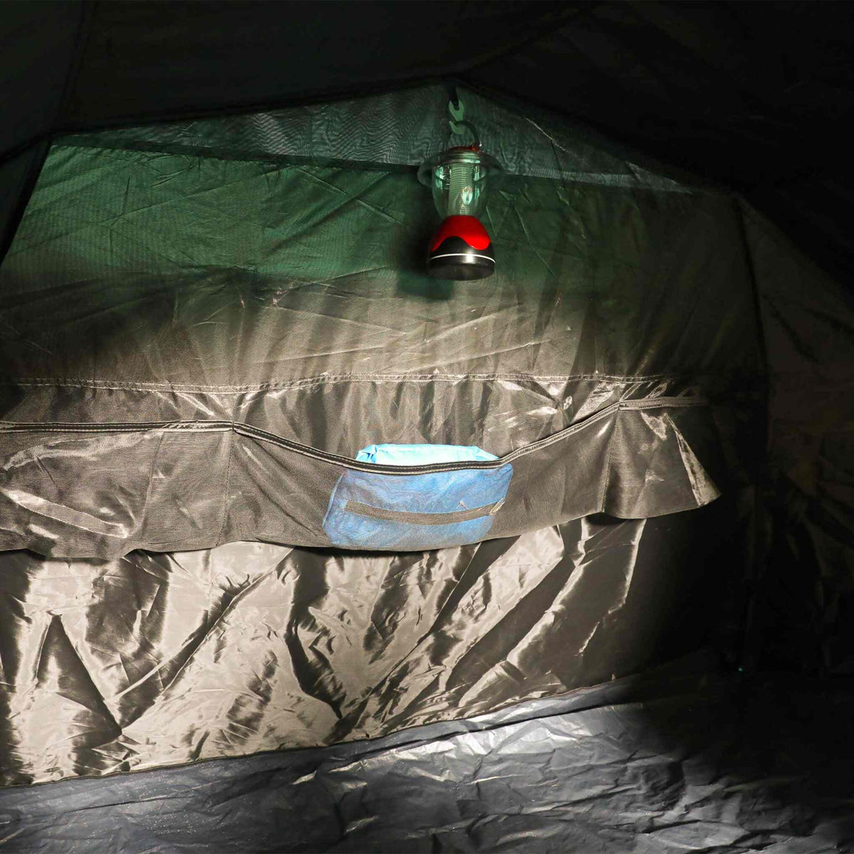 Three-person blackout pop-up tent interior with hanging lantern.